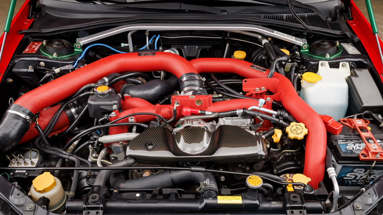 A close-up of a tuned 2005 Subaru WRX STI engine with red details and carbon fiber.