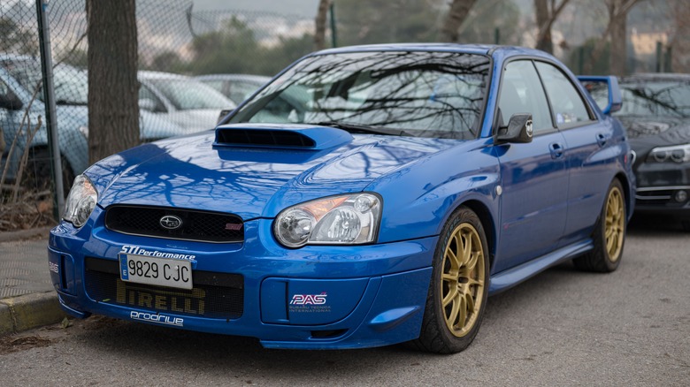 Front 3/4 shot of a blue Subaru Imprezza WRX parked on the side of the road.