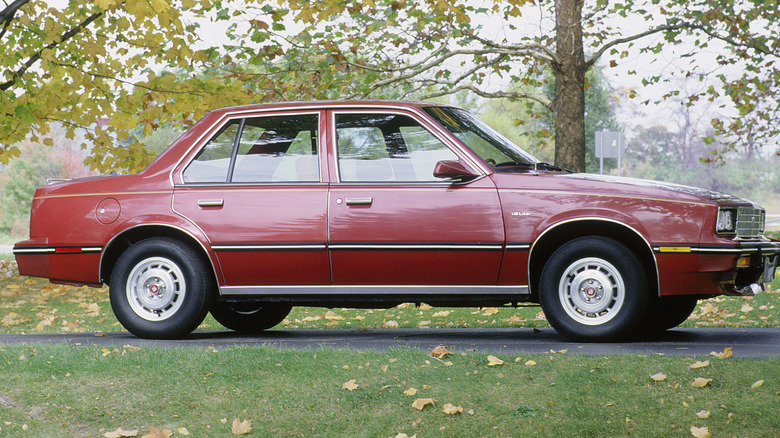A 1983 Cadillac Cimarron parked beside a tree