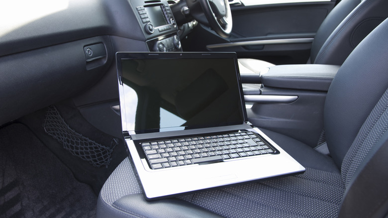 A laptop that's placed on the front seat of a car