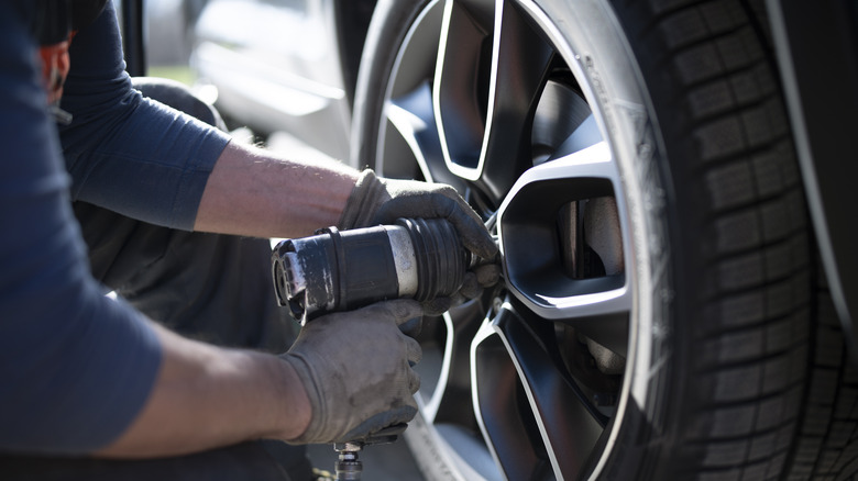 Close-up shot of an auto repairman changing tire in a workshop.