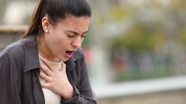 Person clutching at their chest, just below their neck, struggling to breathe.