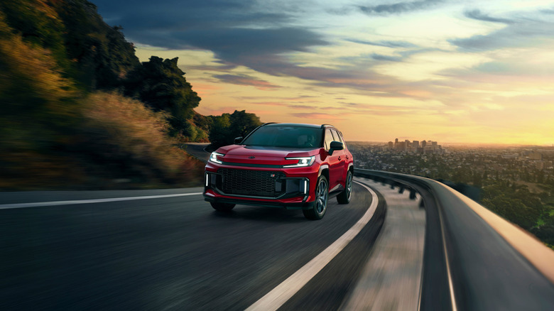 A red 2026 Toyota RAV4 PHEV GR Sport driving, a city far in the background.