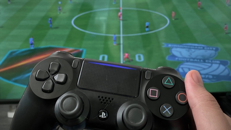person holding PS4 controller playing FIFA