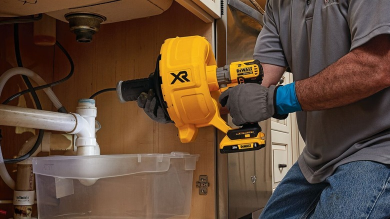 A person using a DeWalt drain snake on a sink.