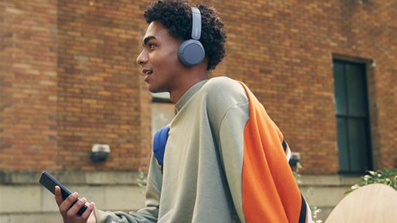 Man wearing headphones and holding a smartphone