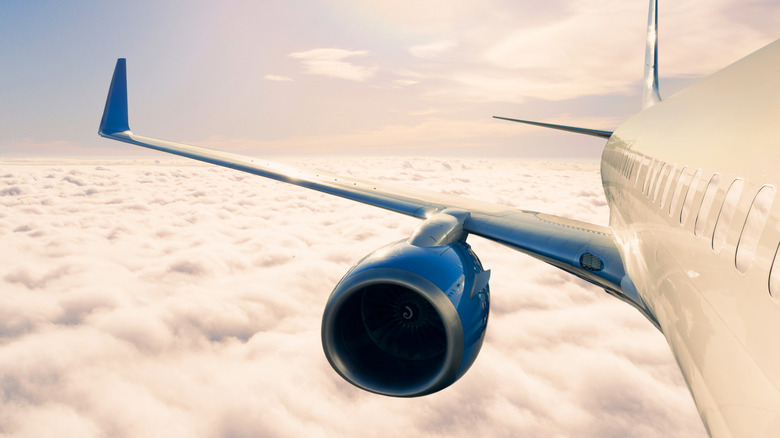 Plane flying over clouds with blue engine