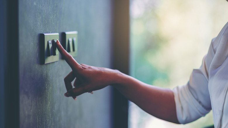 Hand touching a row of light switches