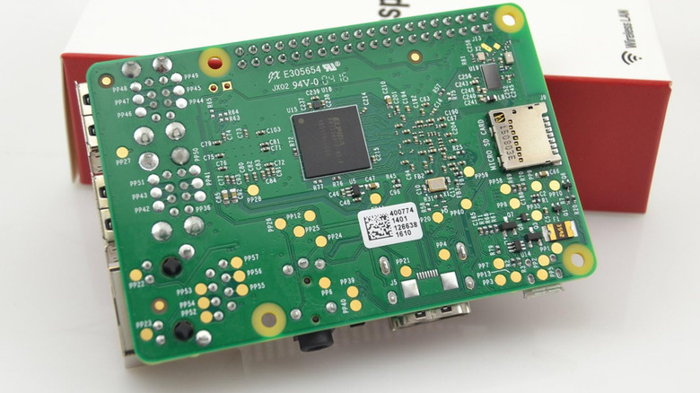 The back of a Raspberry Pi circuit board next to its box.