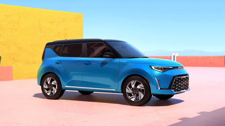 Front 3/4 view of Kia Soul, light blue exterior, colorful architecture