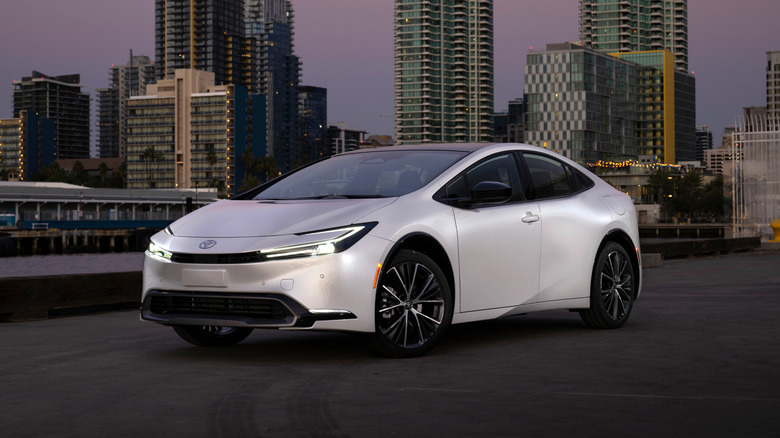 Front 3/4 view of Toyota Prius, white exterior, urban environment at dusk