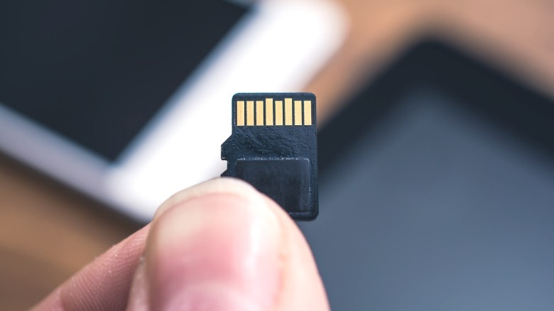A man holding a micro SD card in front of a phone