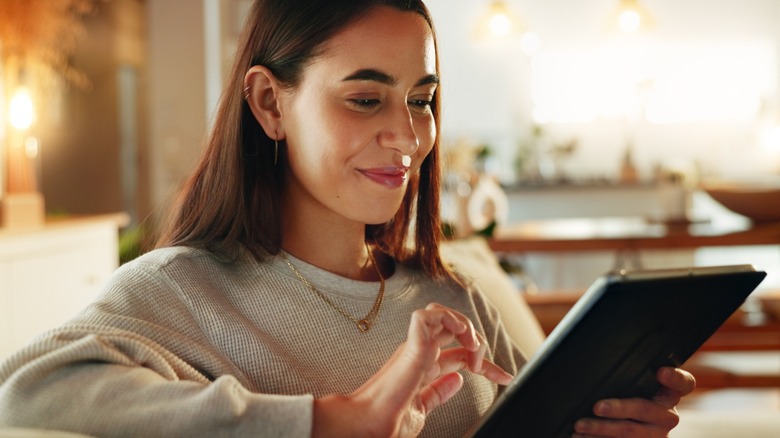 Woman smiling while using her tablet