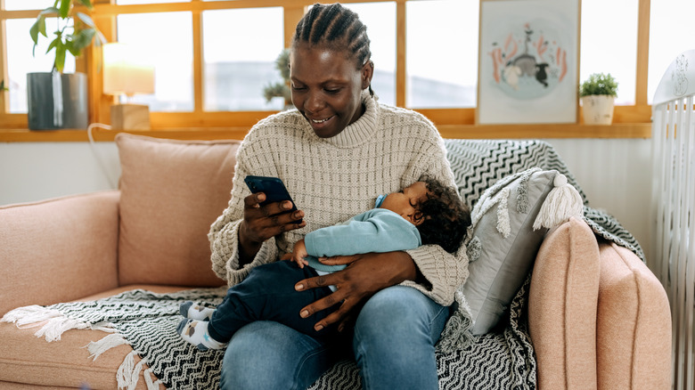 woman holding baby with phone