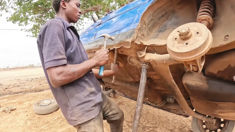 African mechanic working on car raised on poles