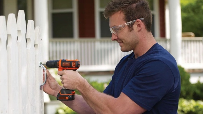 Person drilling fence handle with Black and Decker drill