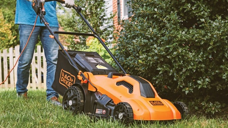 Person mowing lawn with Black and Decker mower