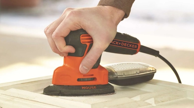 Person sanding wood with Black and Decker mouse sander