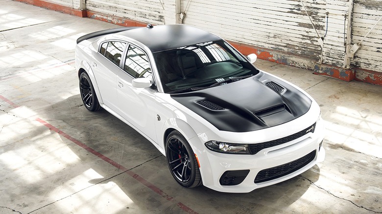 A white Dodge Charger Hellcat Redeye parked on a concrete floor inside an industrial-style space,
