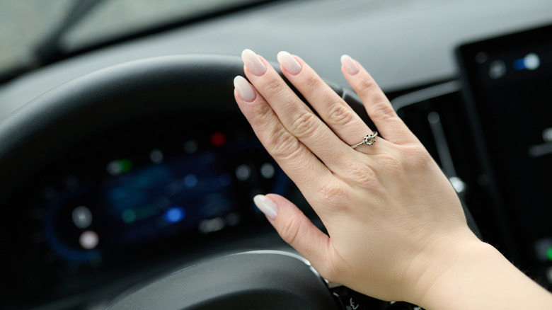 A hand making a gesture on a steering wheel