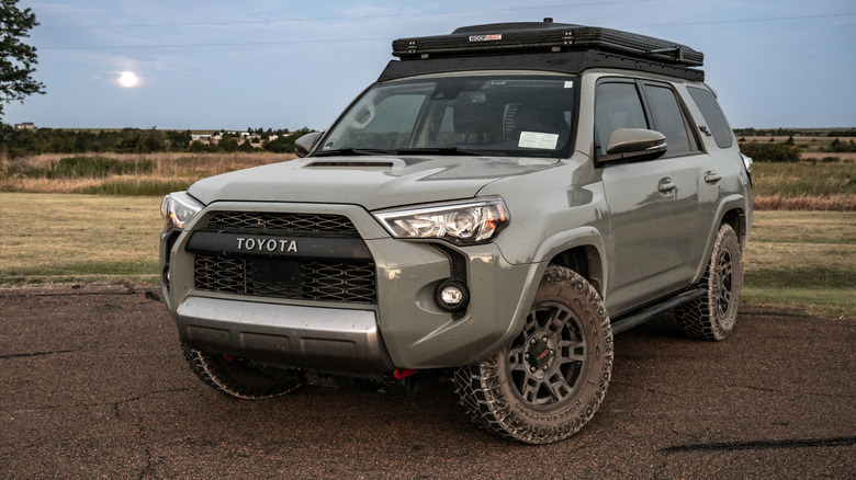 A gray 2024 Toyota 4Runner equipped with a rooftop tent parked, with trees in the background.