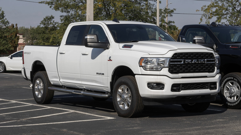 A white RAM 2500 with the crew cab parked in a lot with other cars.