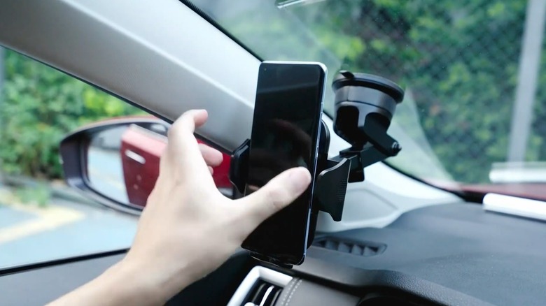 Phone mounted to car windshield use by a hand
