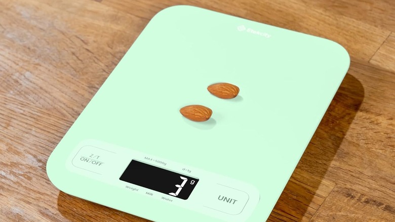 green weighing scale with almonds on a wooden surface