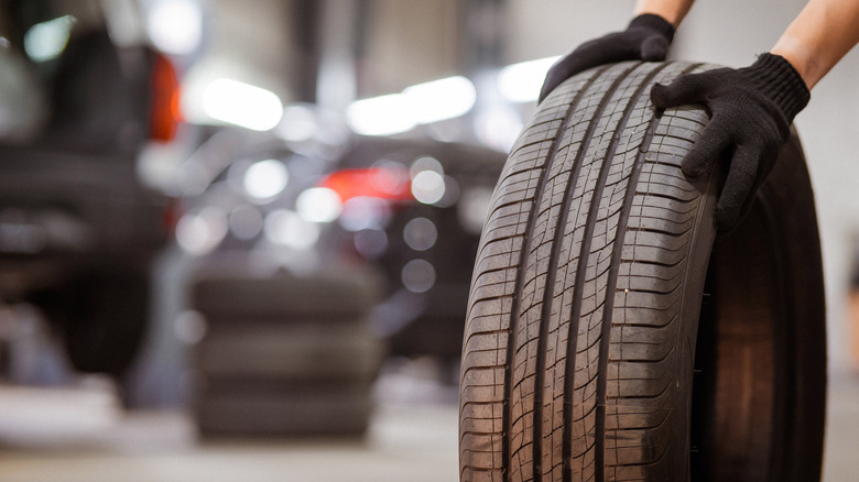 A man in black gloves holding a car tire.