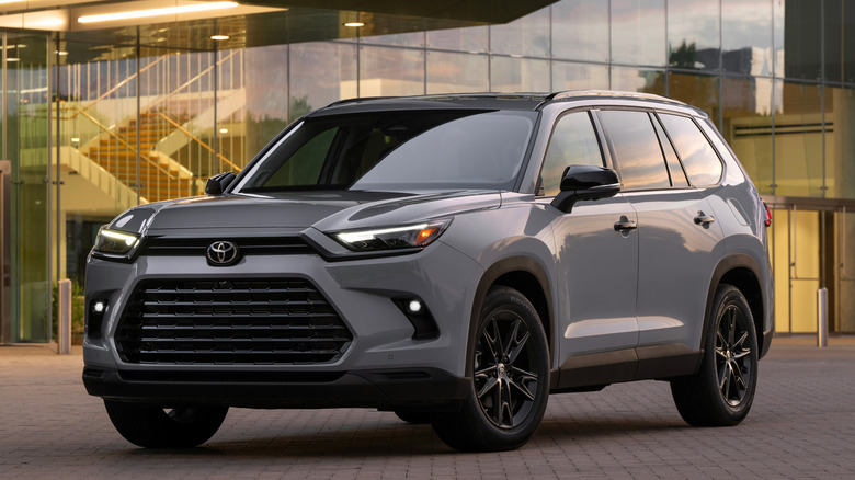 2026 Toyota Grand Highlander parked in front of office building, front-left 3/4 view