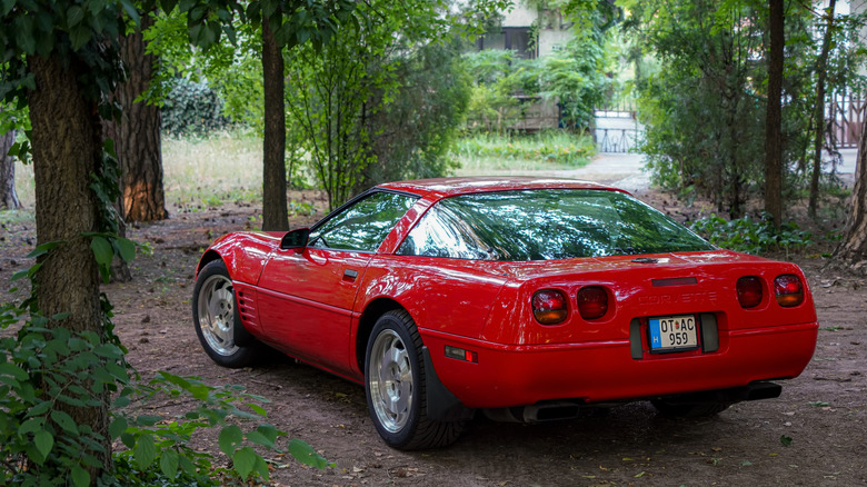 Rear-quarter shot of a C4 Corvette parked among trees