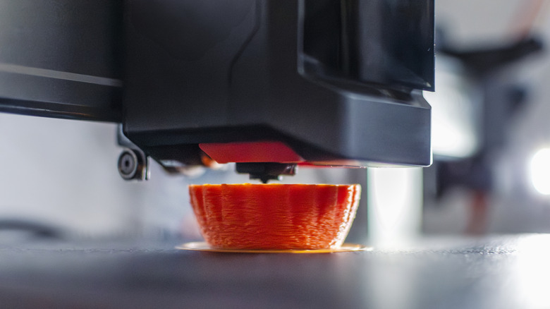 A 3D printer at work on an orange object