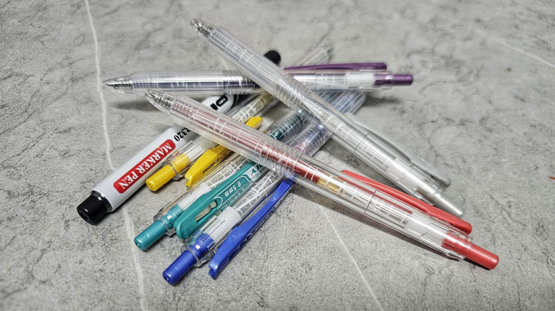 Pens and markers sitting on a gray marbled surface