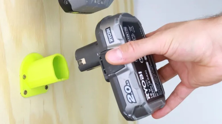 A person putting a Ryobi battery into a 3D printed holder.