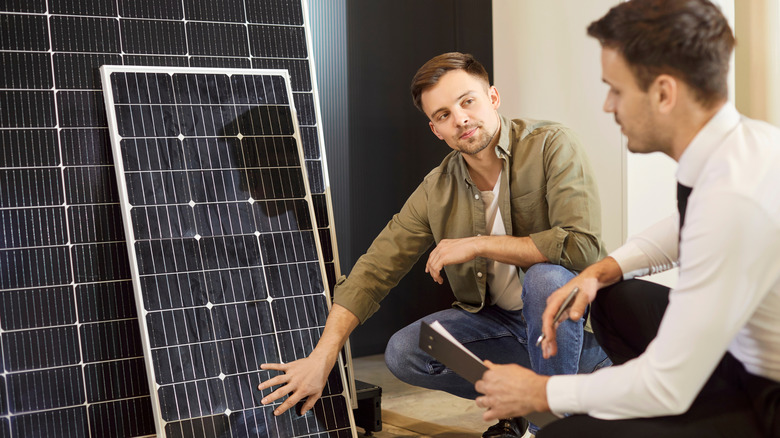 A worker and a customer discussing in front of solar panels