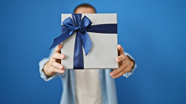 Man holding white gift box over his face
