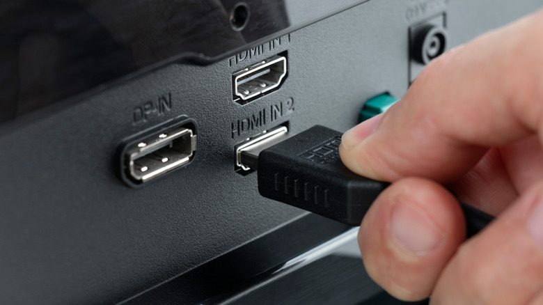 A person connecting an HDMI cable to a TV