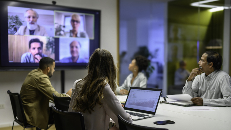 A TV in a boardroom showing an online meeting