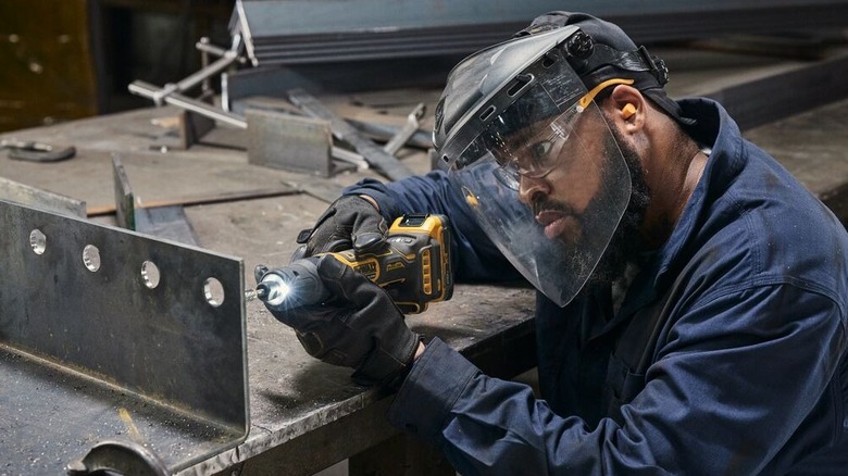 person using die grinder to smooth holes in a piece of metal