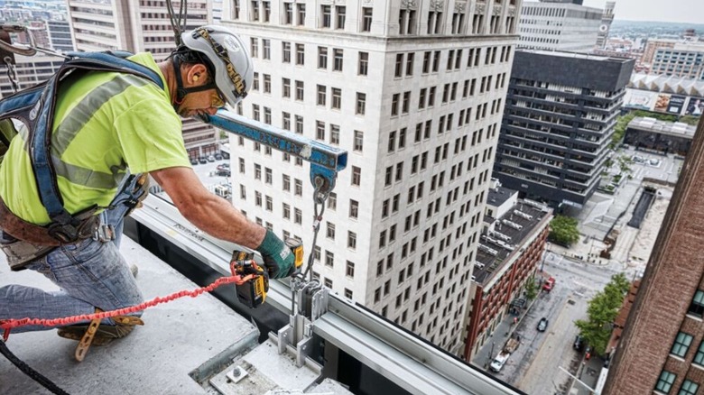 Person on top of a building using a tool with a lanyard attached