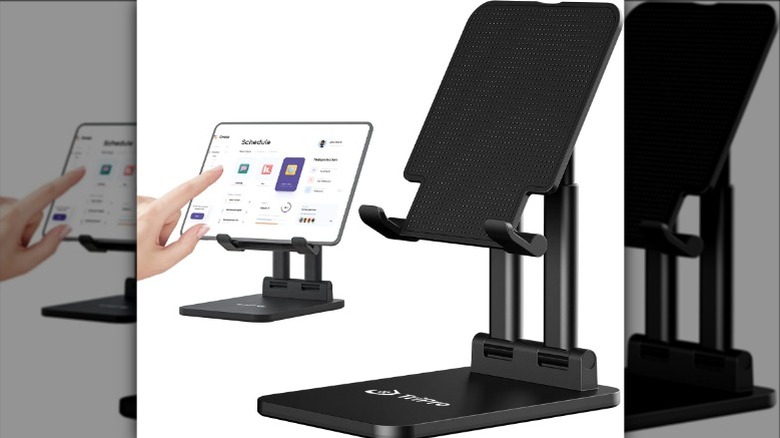 Hands placing a tablet on a black stand