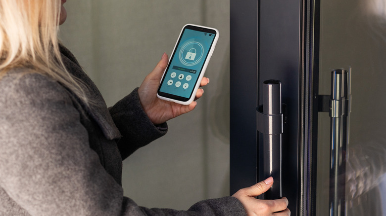 A person seen from behind opening a door with an app on a phone