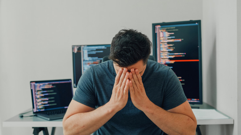 A programmer overwhelmed with head in hands
