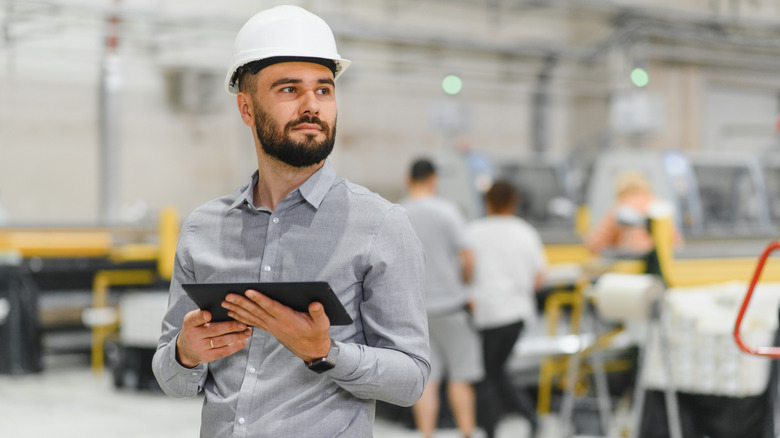 A person in a factory wearing a construction hat