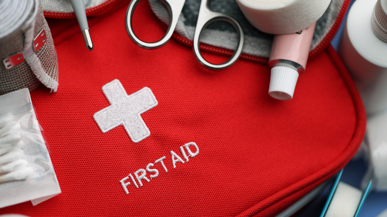 A closeup image of a first aid kit surrounded by supplies