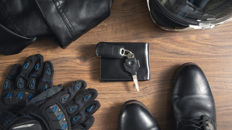 Biking gloves, keys, wallet, and other otheraccessories on top of a table