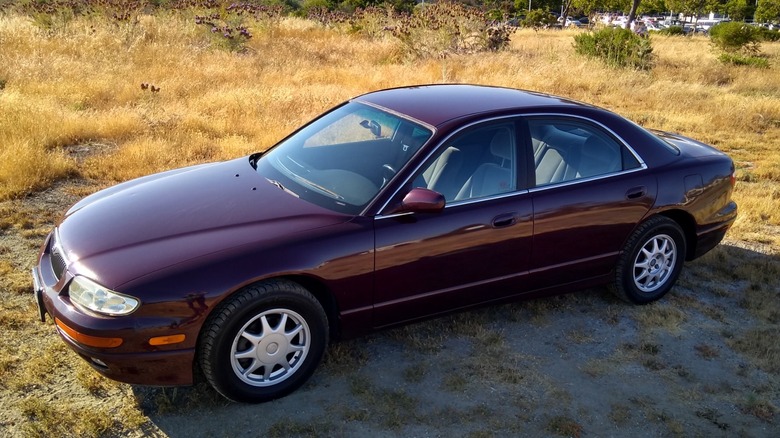 Maroon Mazda Millenia parked on dirt with dry grass in the background