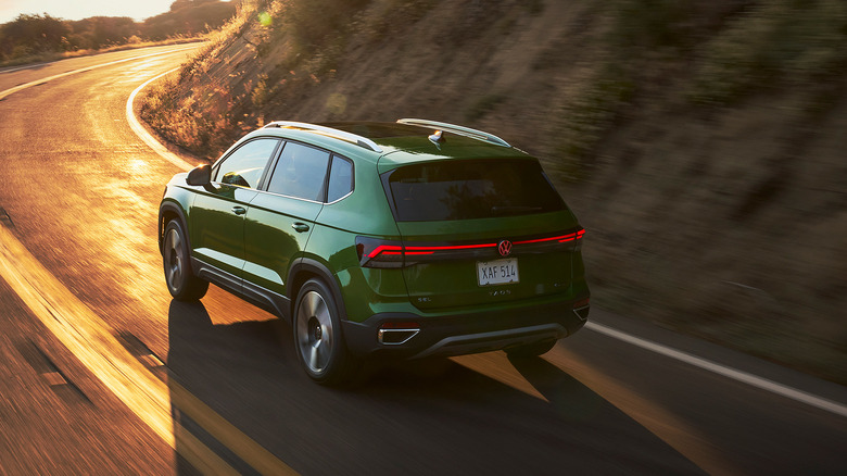 A rear view shot of a green 2026 Volkswagen Taos driving