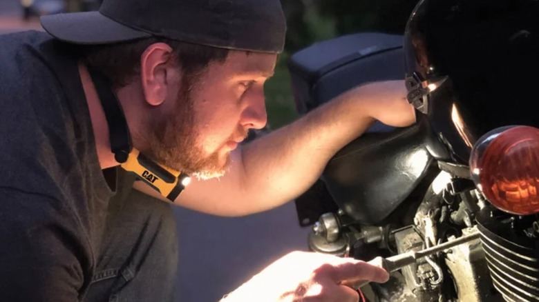 Person using Cat LED Neck Light while working on a motorcycle