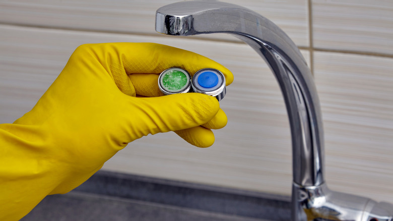 Gloved hand showing faucet aerators